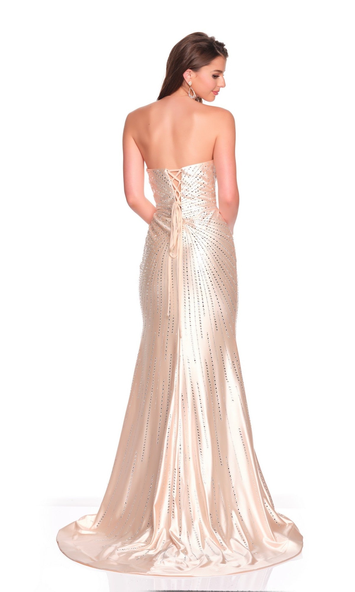 A woman faces away in the Dave and Johnny 12901, a floor-length champagne satin prom dress with rhinestone details, strapless neckline, and lace-up back.